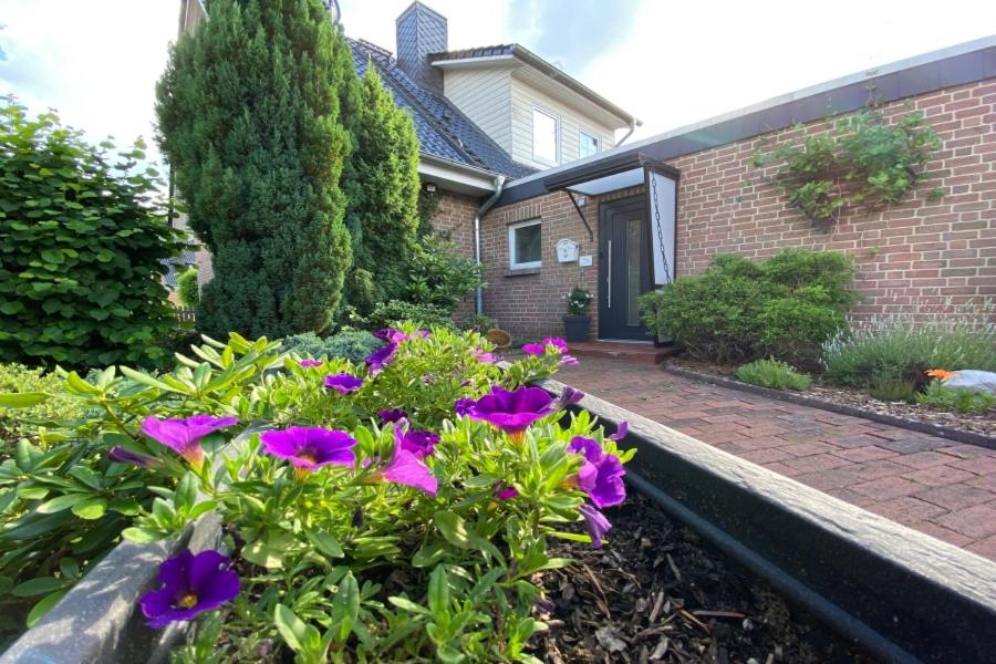 um jardim com flores roxas em frente a uma casa em Ferienapartment Weber em Faßberg