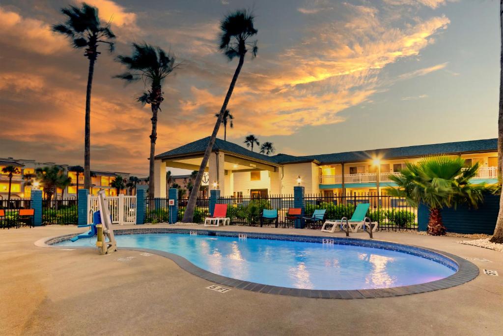 a swimming pool in front of a house with palm trees at Captains Quarters Inn in Port Aransas