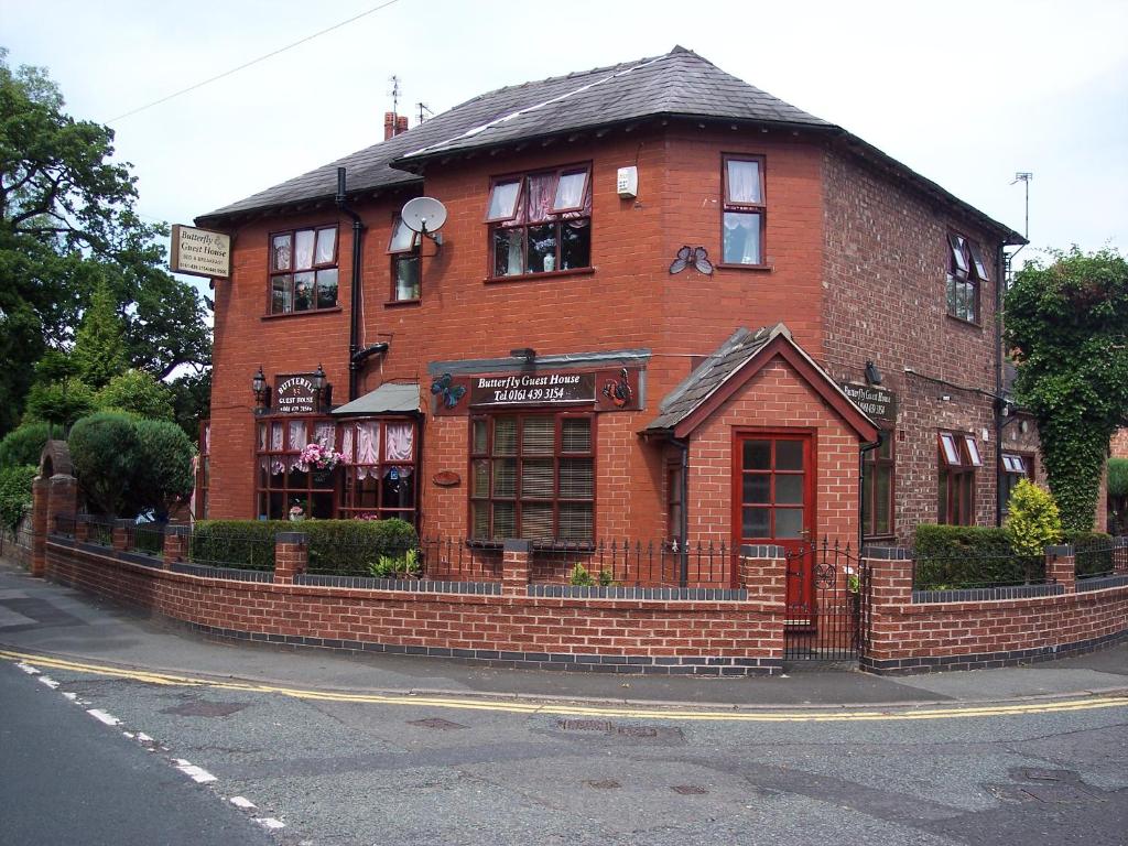 un edificio de ladrillo rojo en la esquina de una calle en Butterfly Guest House, en Cheadle