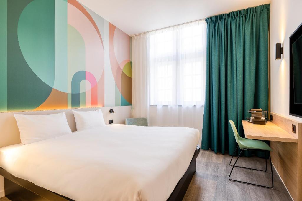 a hotel room with a white bed and a desk at B&B HOTEL Hasselt in Hasselt