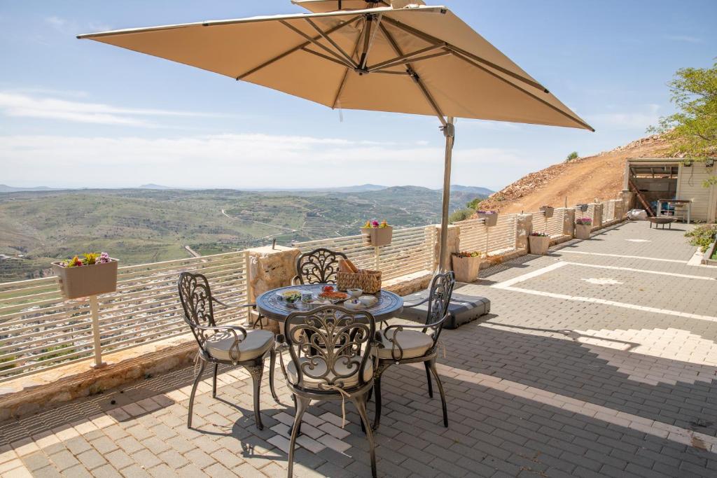 un patio con mesa, sillas y sombrilla en צימר ענאן בגולן, en Majdal Shams