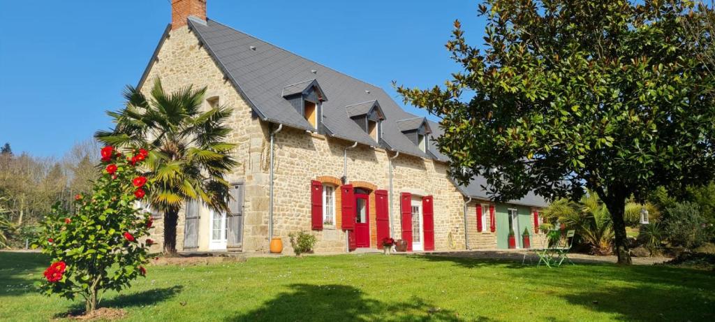 Isigny-le-Buat的住宿－La Pichonnière，红百叶窗和一棵树的砖屋