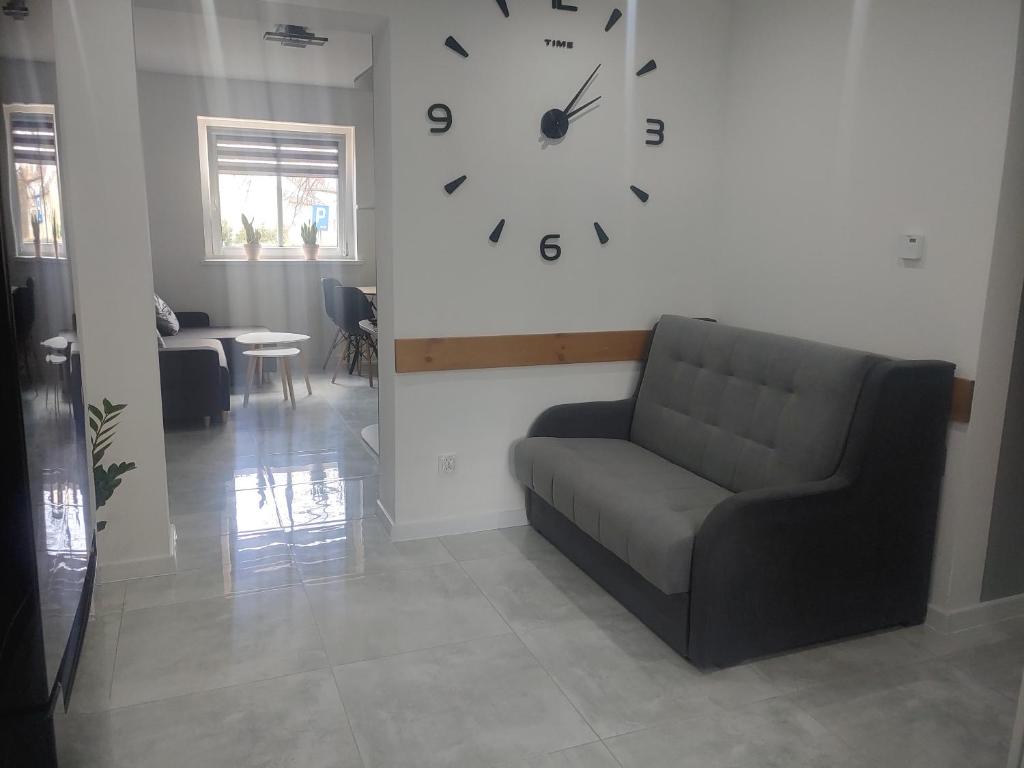 a living room with a couch and a clock on the wall at APARTAMENT PRZY RONDZIE in Kłodzko
