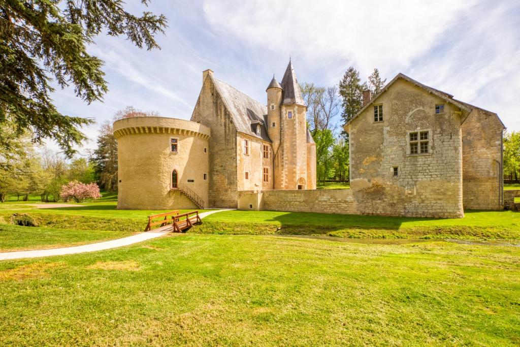 un viejo castillo en un campo de hierba con un banco en Château de Vieux Moulin 