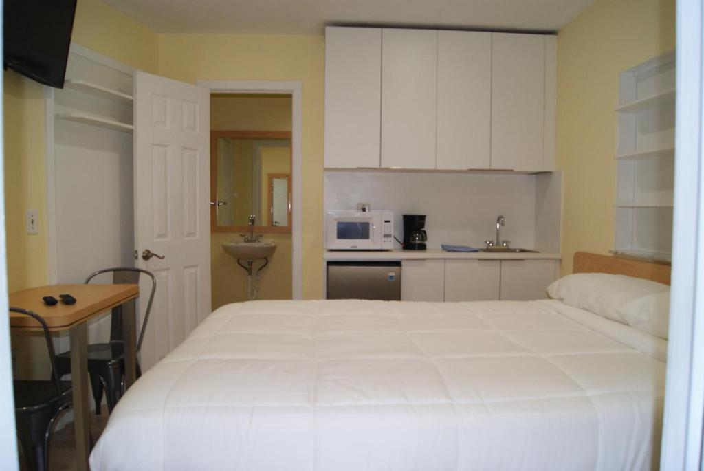 a bedroom with a large white bed and a kitchen at Private Studio two miles from Hard Rock Stadium in Miami Gardens