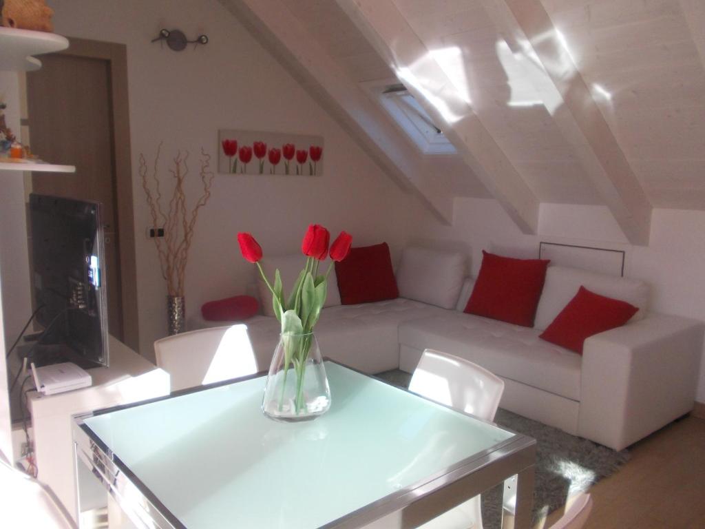 un vase avec des fleurs rouges sur une table dans le salon dans l'établissement A casa di Laura Finale Ligure, à Finale Ligure