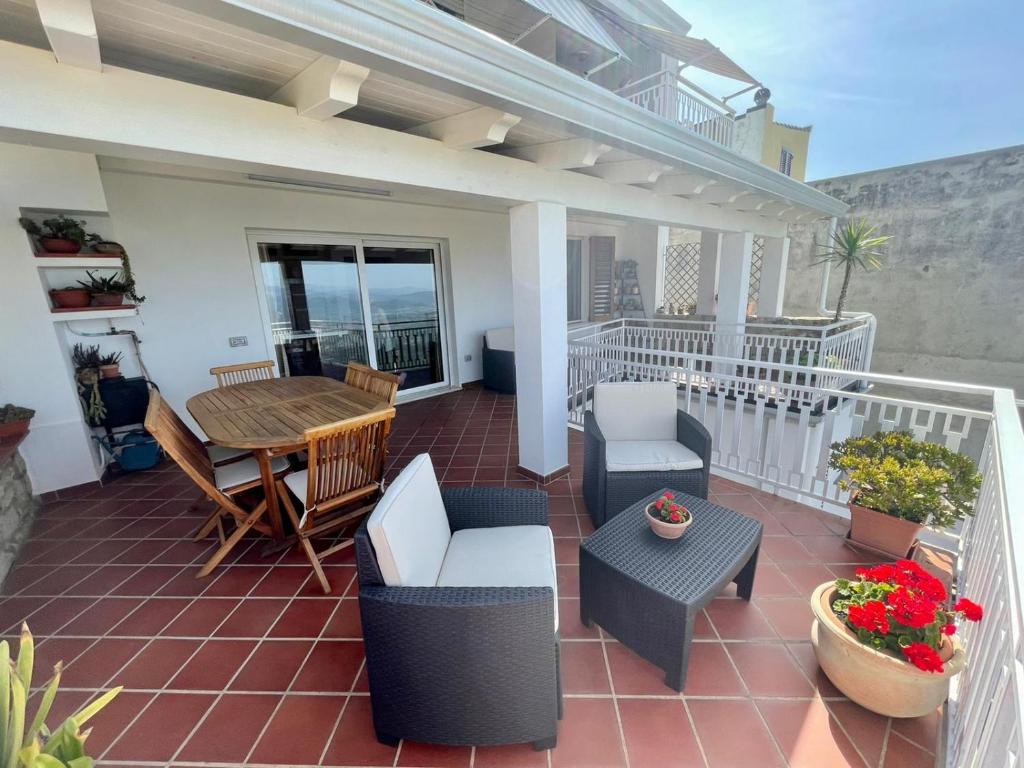 patio con mesa y sillas en el balcón en Appartamento con Vista Panoramica, en Baunei