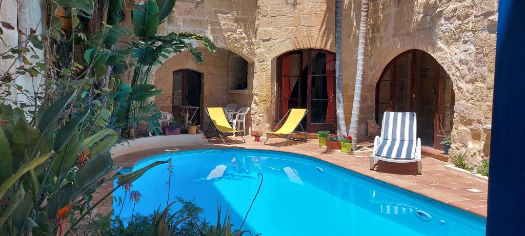 a swimming pool with two lawn chairs next to a building at Haven Farmhouse B&B in Għarb