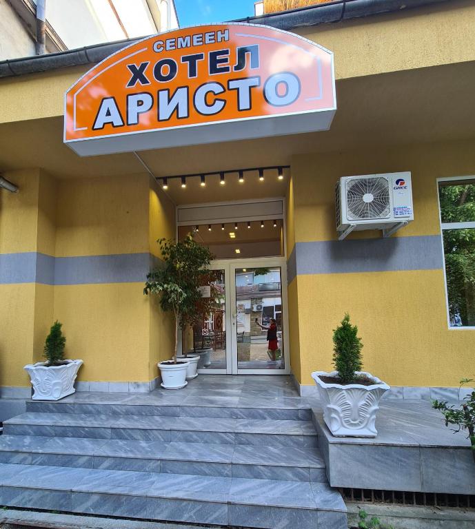 a yellow building with a sign for a vet appartment at Семеен хотел Аристо in Dryanovo