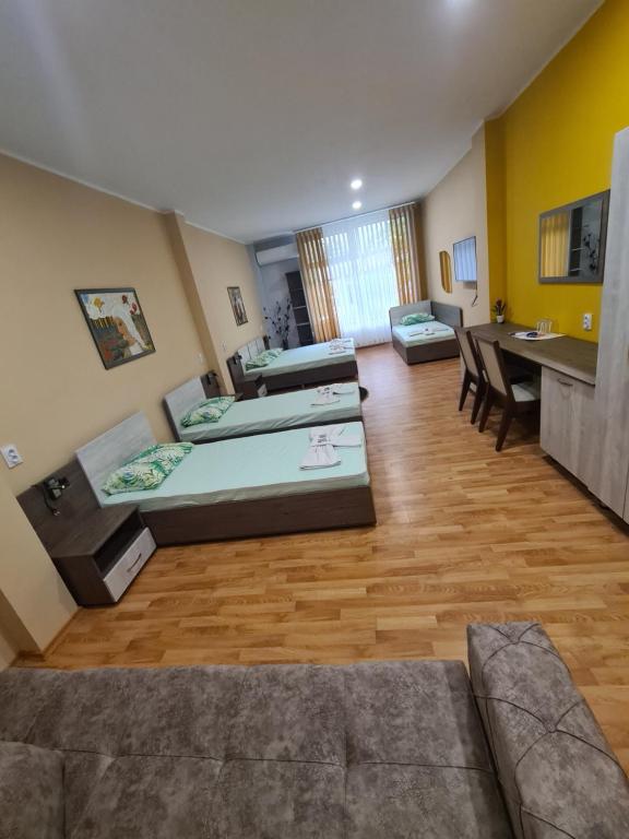 Cette grande chambre comprend deux lits et une table. dans l'établissement Семеен хотел Аристо, à Dryanovo