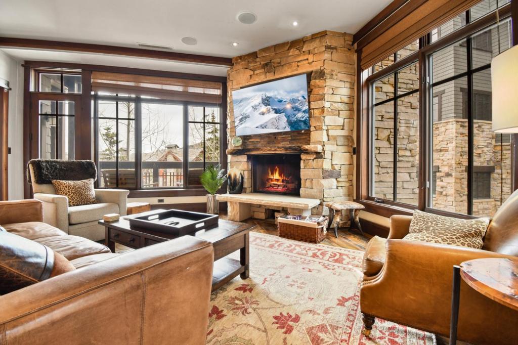 a living room with a fireplace and a stone wall at Arrowleaf Lodge - 3 Bed Condo #302 in Park City