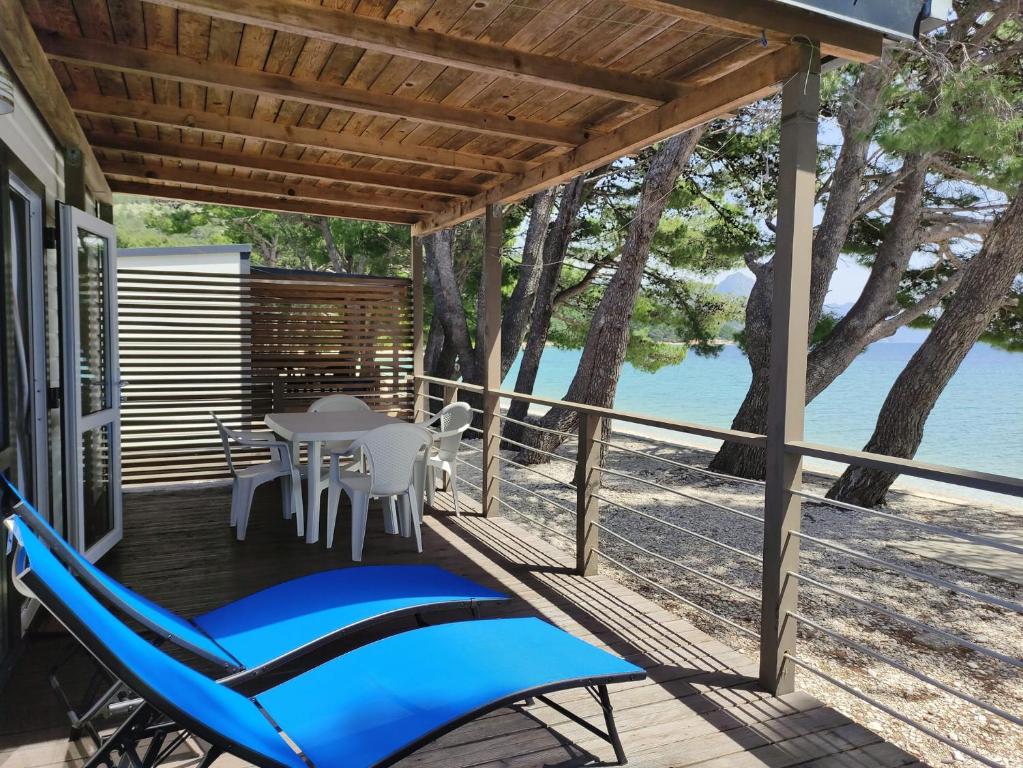 eine Terrasse mit einer blauen Hängematte sowie einem Tisch und Stühlen in der Unterkunft Kamp Dole - Navores in Živogošće