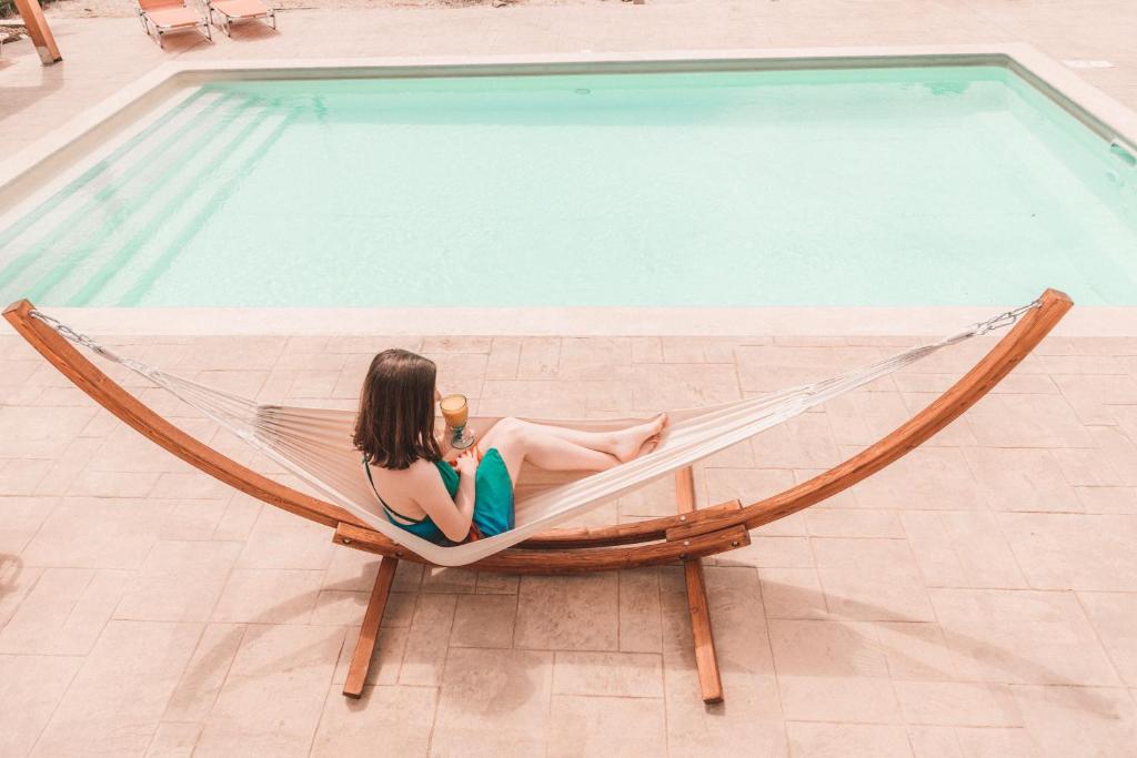 eine Frau, die in einer Hängematte neben einem Pool sitzt in der Unterkunft Almyra Apartments & Suites in Sfakaki