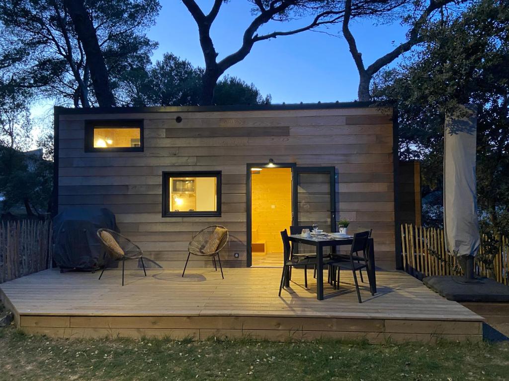 uma pequena casa com uma mesa e cadeiras num deque em TINY HOUSE LA FARIGOULE em Pélissanne