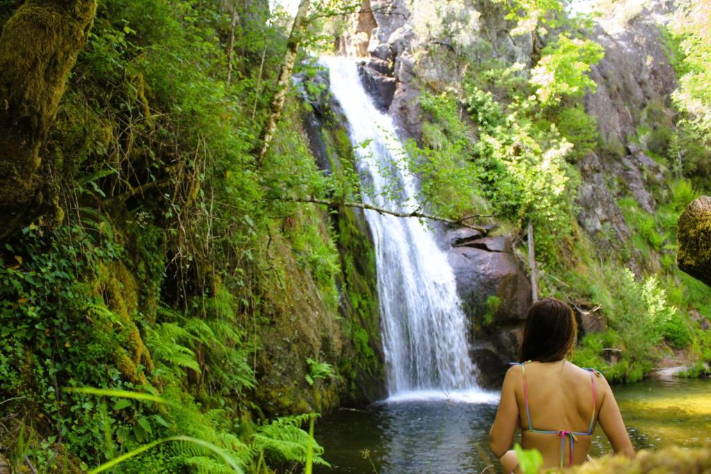 a woman in a bikini standing in front of a waterfall at Casa Boletus in Castro Laboreiro