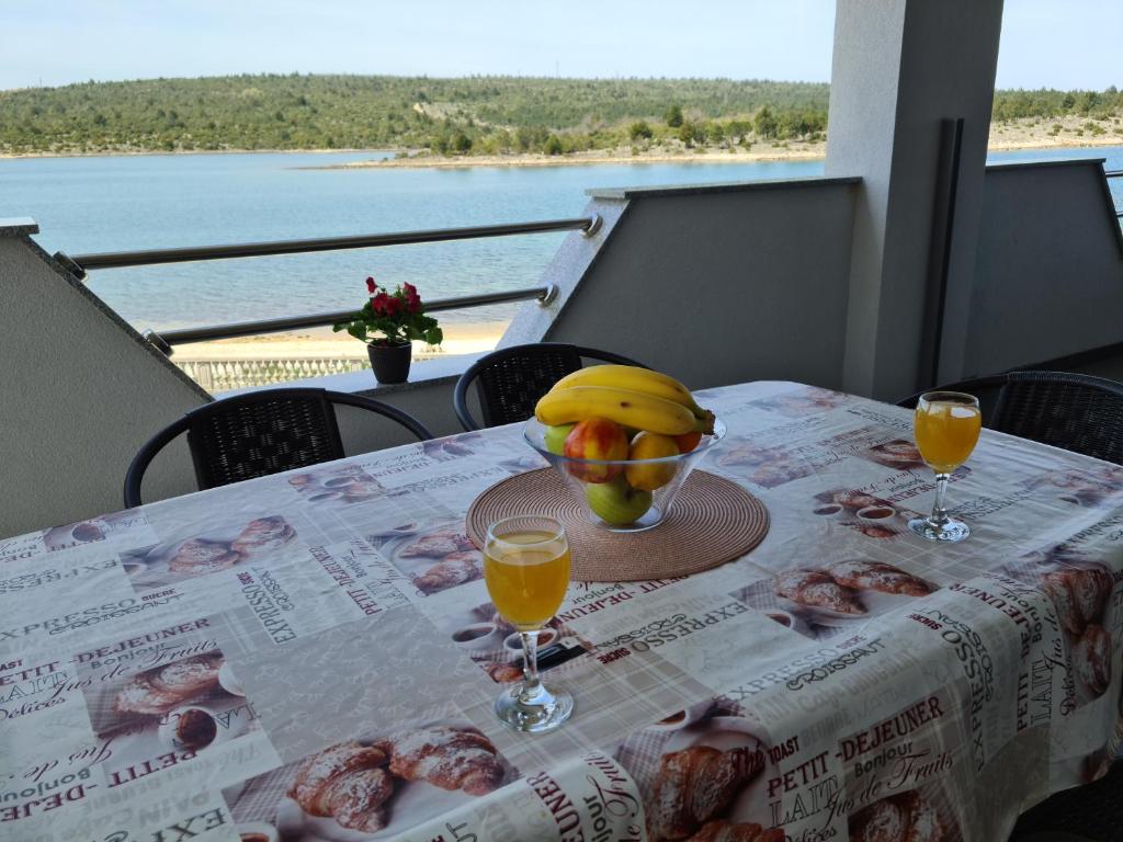 einen Tisch mit einer Schale Obst und zwei Gläsern Orangensaft in der Unterkunft Apartmani Rudi in Anić