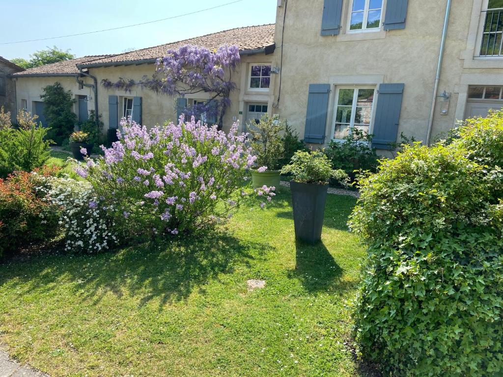 um quintal com flores em frente a uma casa em Chambres d’hôtes la bottée em Viéville-sous-les-Côtes