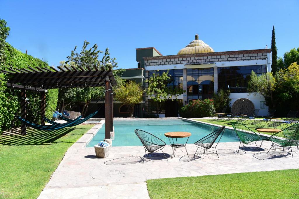 una piscina con sillas y una mesa junto a un edificio en Hacienda San Patricio, en San Miguel de Allende