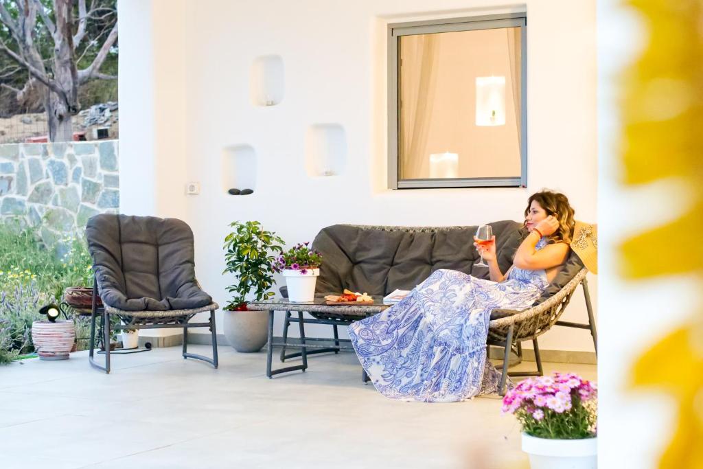 a woman sitting in a chair on a patio at Cycladic Home on the hill with beautiful views!! in Agkidia