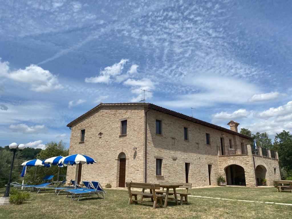 un gran edificio de piedra con mesas de picnic y sombrillas en Agriturismo Cà Ferro en Urbino