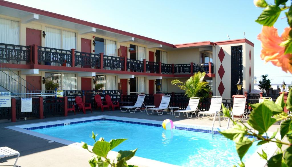 a hotel with a swimming pool and chairs and a building at Casa Del Sol Motel in Wildwood