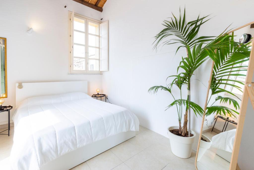 a bedroom with a white bed and a potted plant at Penthouse with Terrace in historic centre in Cagliari