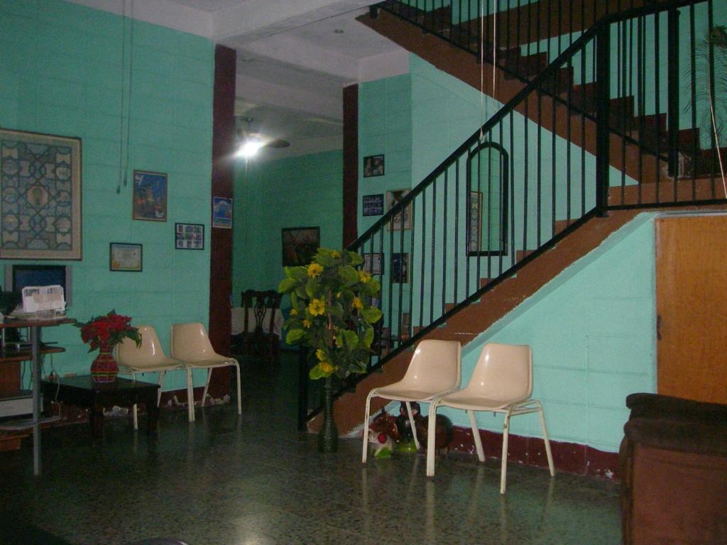 a room with chairs and a staircase with a plant at Guesthouse Dos Molinos B&B in San Pedro Sula