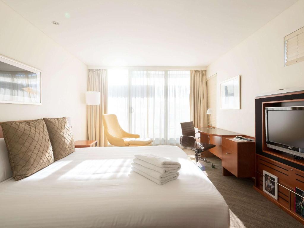 Habitación de hotel con cama y TV de pantalla plana. en Novotel Canberra en Canberra