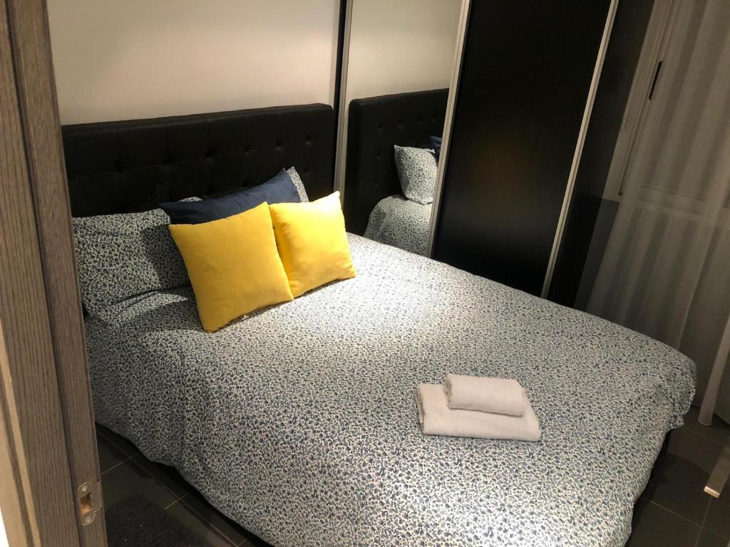 Elche piso entero 3 dormitorios dobles في إلتشي: سرير مع وسائد صفراء و زرقاء ومرآة