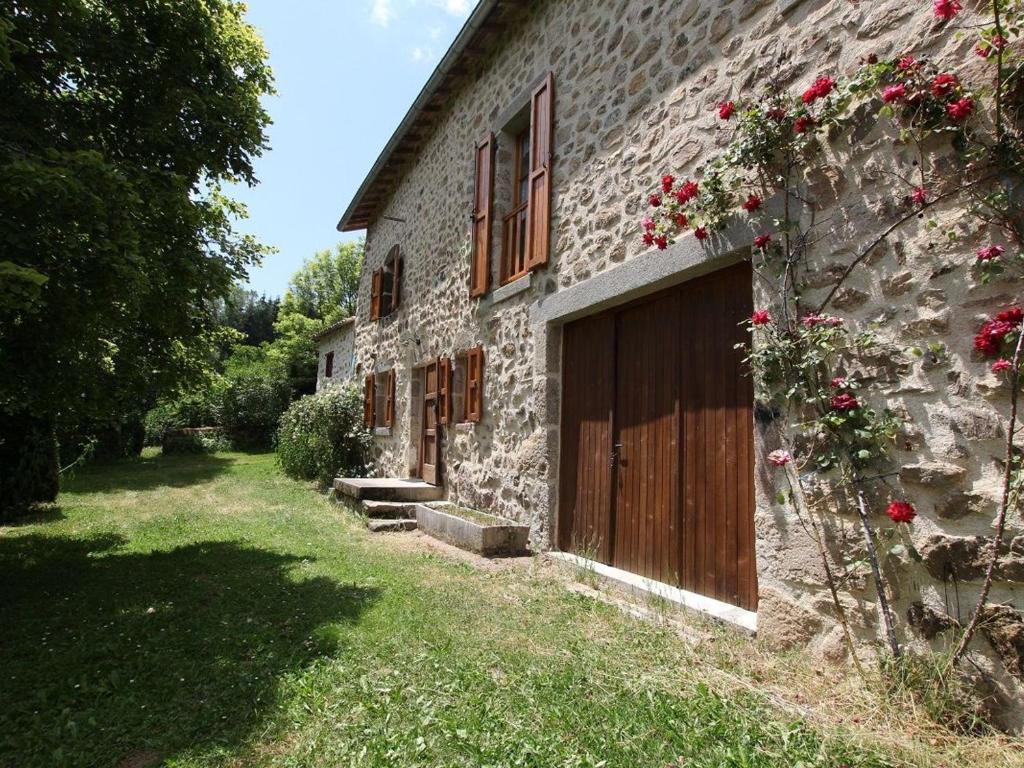 a stone building with a wooden door and flowers at Gîte Allègre, 4 pièces, 6 personnes - FR-1-582-151 in Allègre