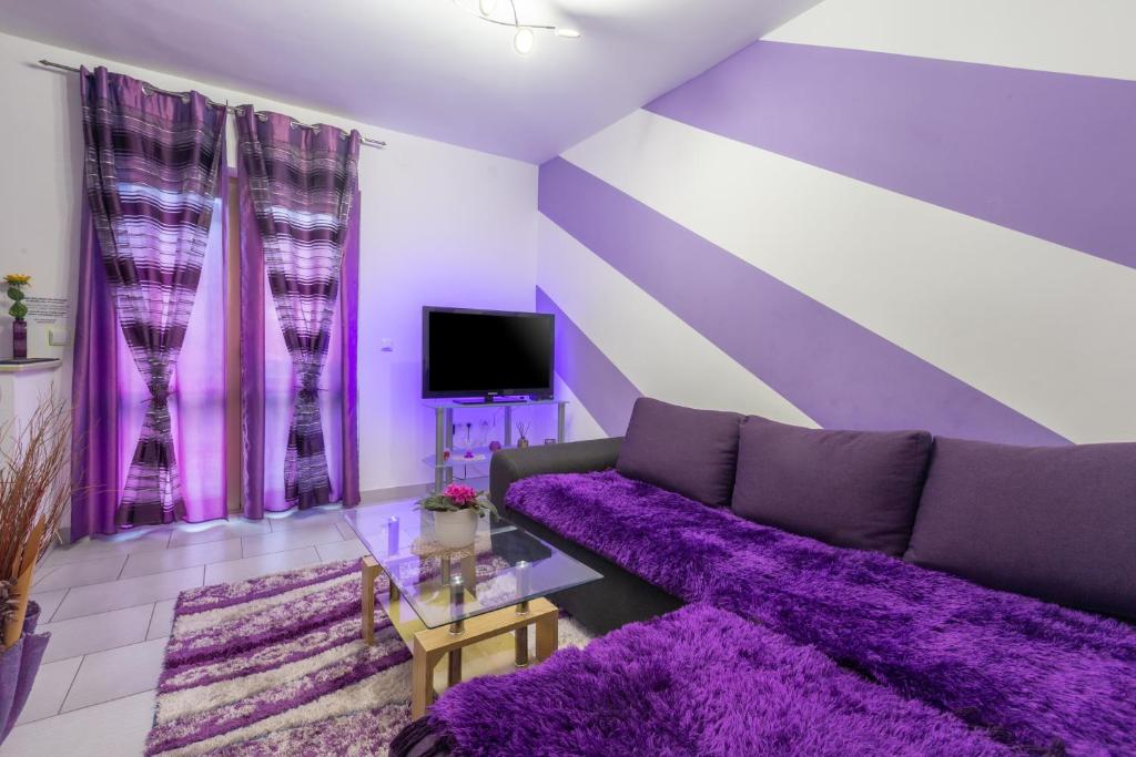 a purple living room with a couch and a tv at Apartment Belma Poreč in Radmani