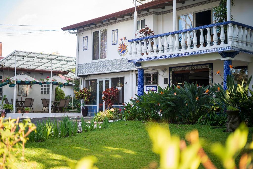 a white house with a balcony and a yard at Hotel Ave del Paraíso in San José