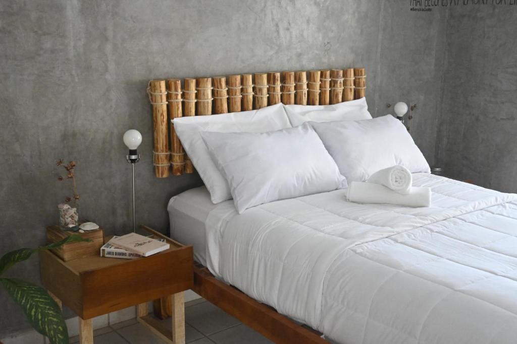 a bedroom with a white bed with a wooden headboard at Desert Heart Hostel in San José del Cabo
