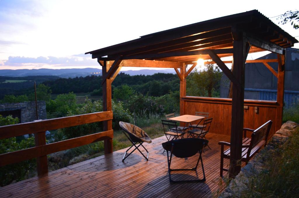 Una terraza de madera con una mesa y sillas. en Les Gites Du Mazel, en champis