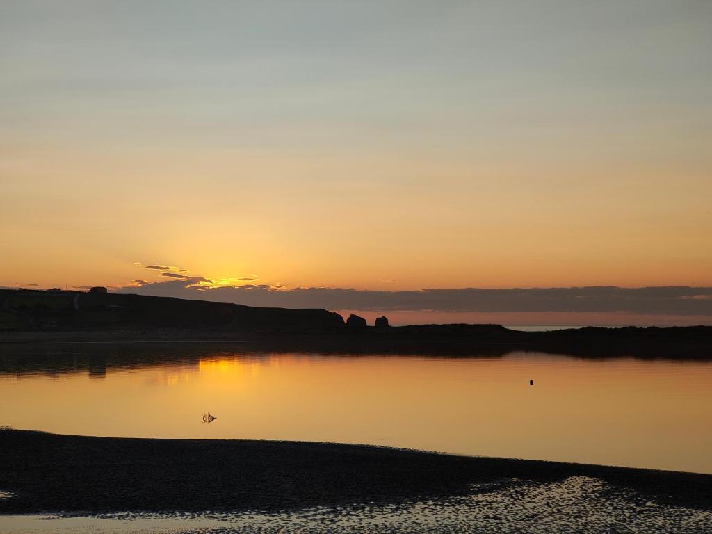una puesta de sol sobre un cuerpo de agua con la puesta de sol en APARTAMENTO PLAYA DE USIL en Mogro