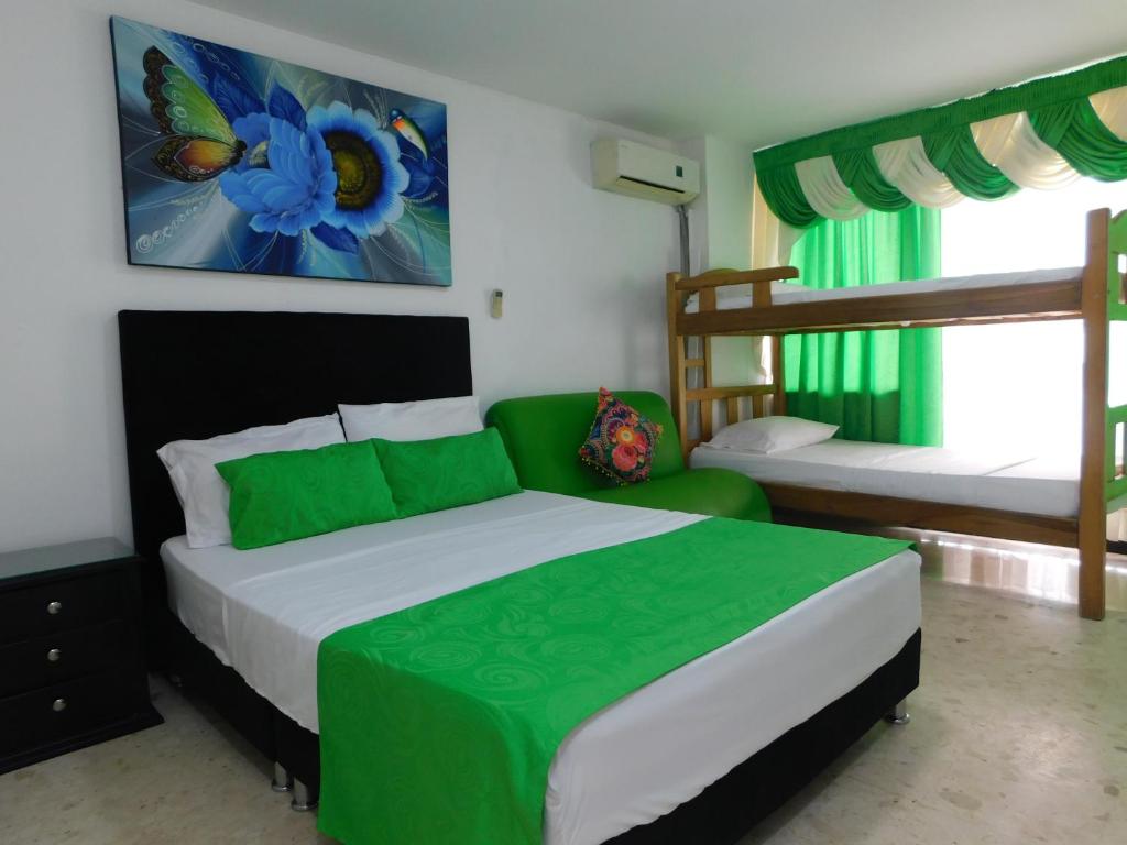 Karey Apartamentos By Danp في سانتا مارتا: غرفة نوم مع سرير لحاف أخضر و أبيض