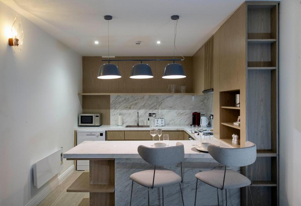 a kitchen with a large island with two chairs at Trueman Court Luxury Serviced Apartments in Liverpool