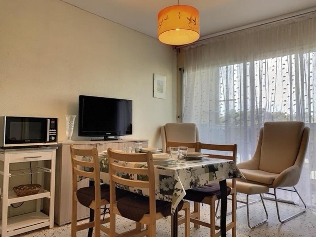 une salle à manger avec une table, des chaises et une télévision dans l'établissement Appartement cosy proche des Thermes avec balcon, WiFi et parking - FR-1-503-117, à Balaruc-les-Bains