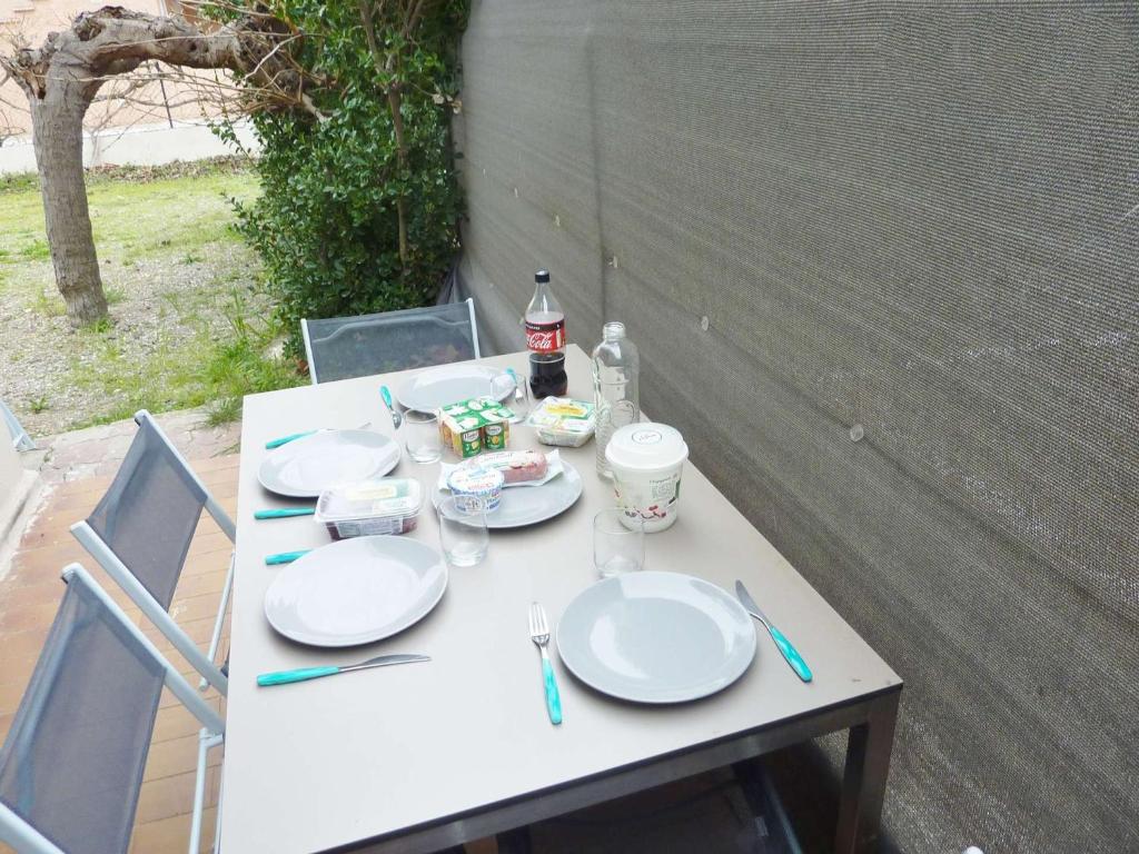 - une table blanche avec des assiettes et des boissons dans l'établissement Appartement T2 rénové, climatisé, avec terrasse et parking, proche plage - FR-1-387-166, à Marseillan