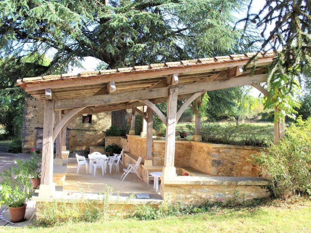 Un pabellón de madera con mesas y sillas en un jardín. en Charmante maison à la ferme avec jardin, terrasse, BBQ, proche sites touristiques, animaux bienvenus - FR-1-616-125, en Saint-Pardoux-et-Vielvic