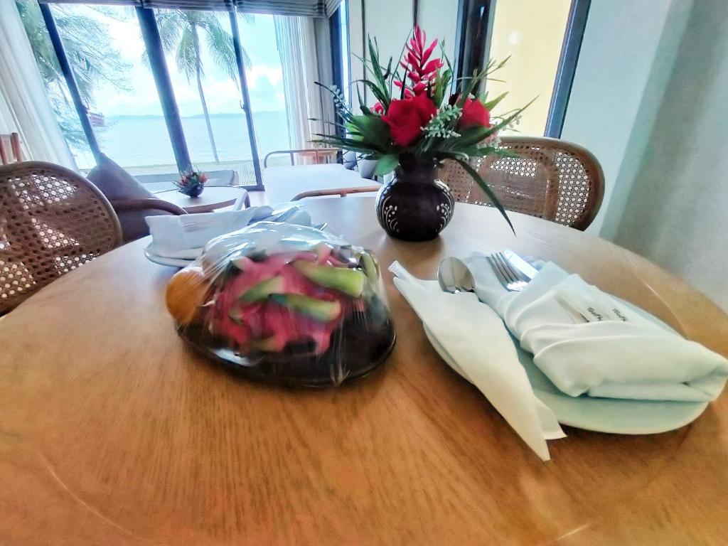 a wooden table with a vase of flowers on it at Supalai Scenic Bay Resort And Spa, SHA Extra Plus in Por Bay