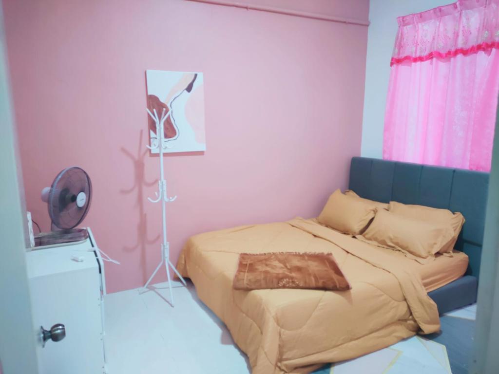 a bedroom with a bed and a pink wall at Yoni Homestay in Kampung Raja
