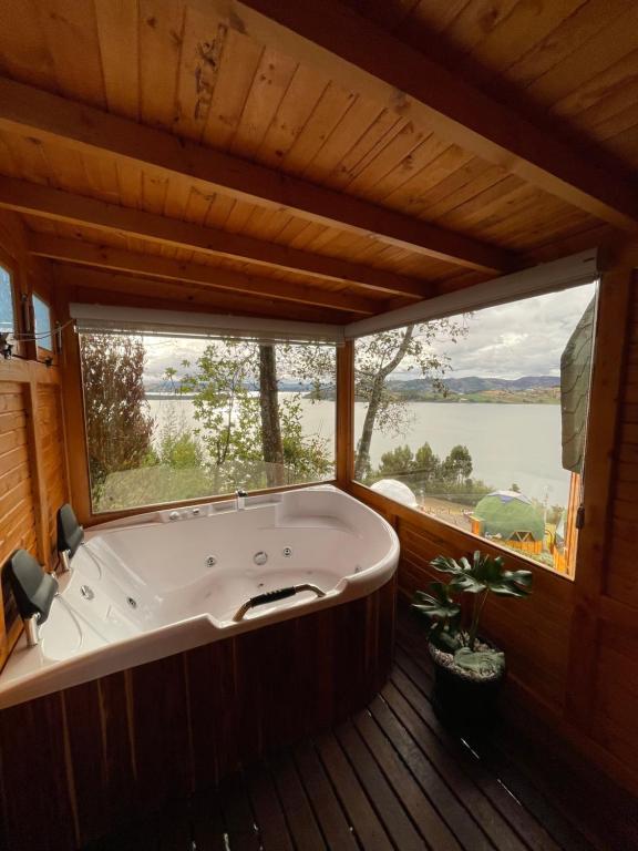 a large bath tub in a room with a large window at Glamping Domos del Lago in Aquitania