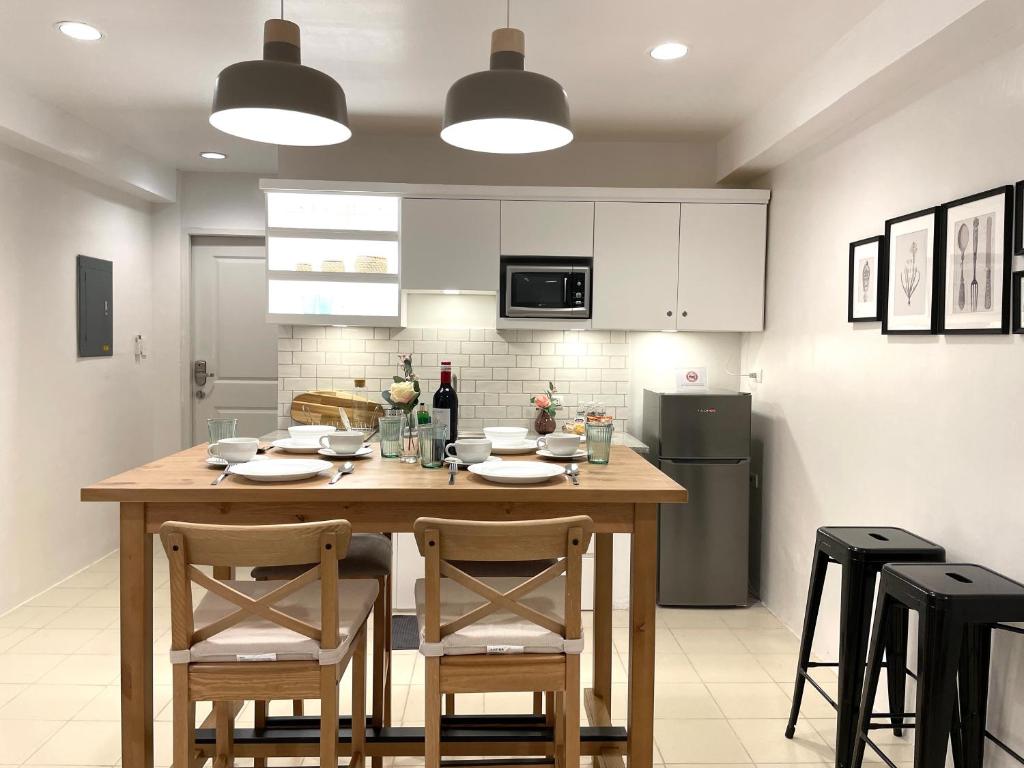 uma cozinha com uma mesa de madeira com cadeiras e um frigorífico em CRIB 227: Modern Fresh Vibe Condo em Olongapo