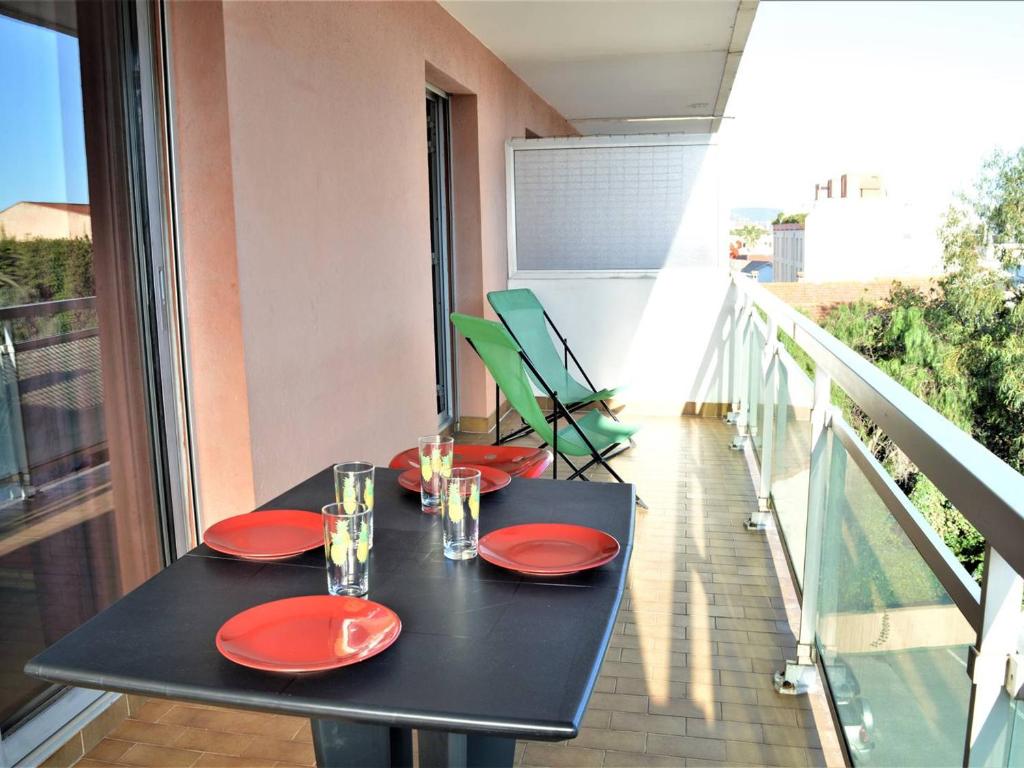 une table noire avec des assiettes rouges et des verres sur un balcon dans l'établissement Appartement Climatisé 2P avec Parking, Proche Plage et Commerces à Cavalaire - FR-1-226B-99, à Cavalaire-sur-Mer
