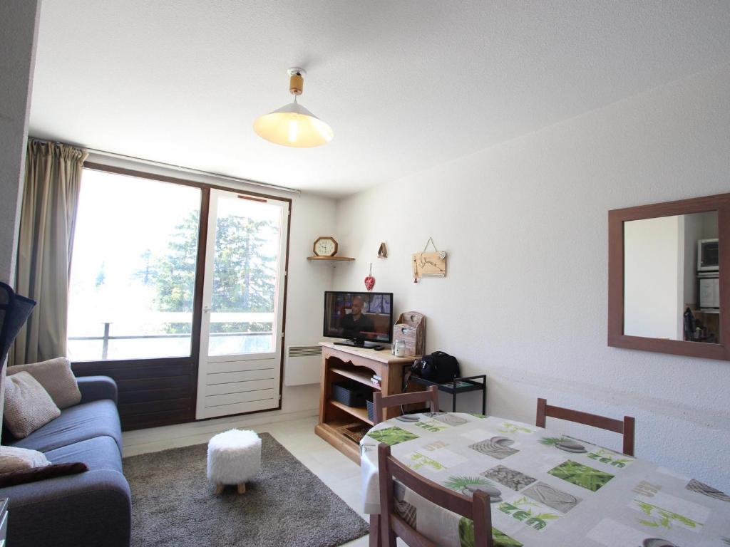 a living room with a table and a couch and a television at Appartement Chamrousse, 2 pièces, 5 personnes - FR-1-549-83 in Chamrousse