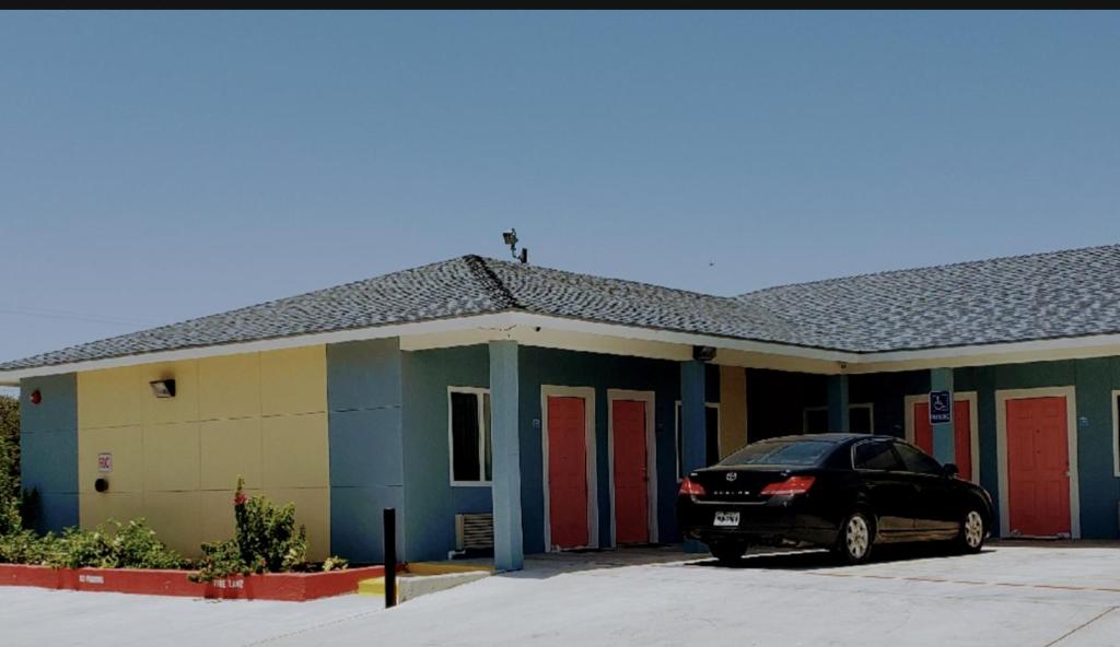 une voiture garée devant un bâtiment avec portes rouges dans l'établissement Holiday Inn motel, à Aransas Pass