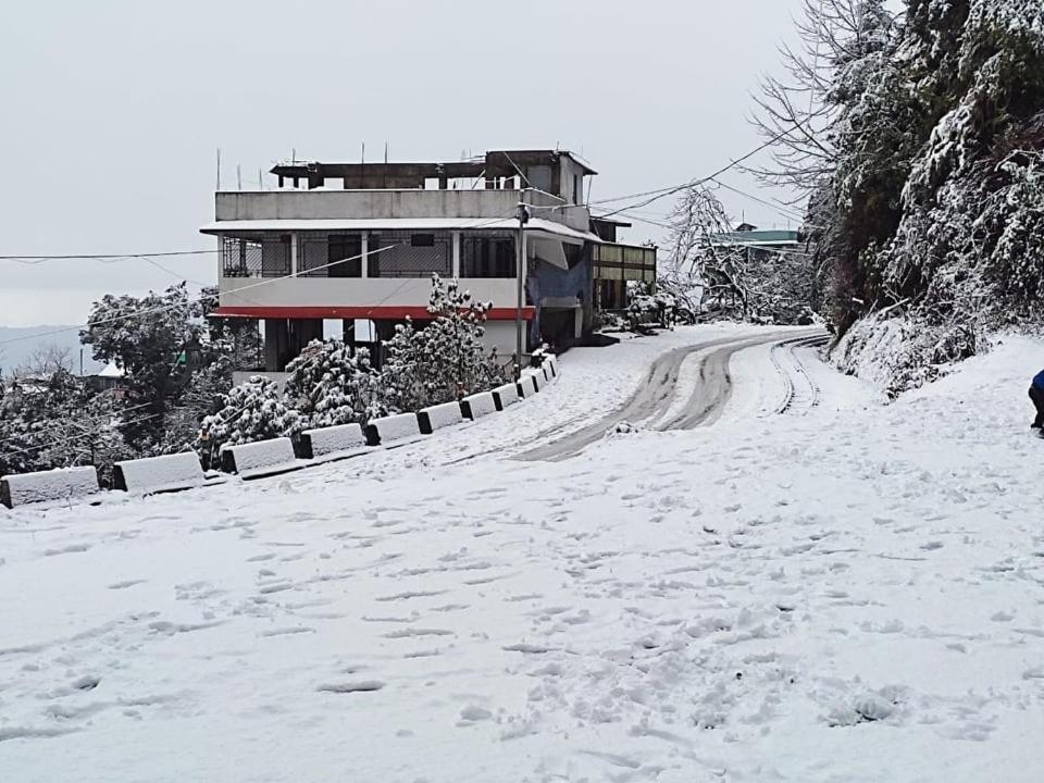 uma estrada coberta de neve com uma casa ao fundo em RHODODENDRON stay em Darjeeling
