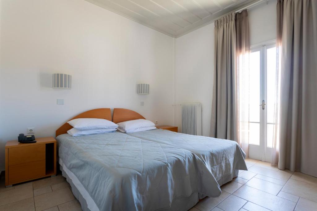 a white bedroom with a bed and a window at Hotel Roumani in Spetses