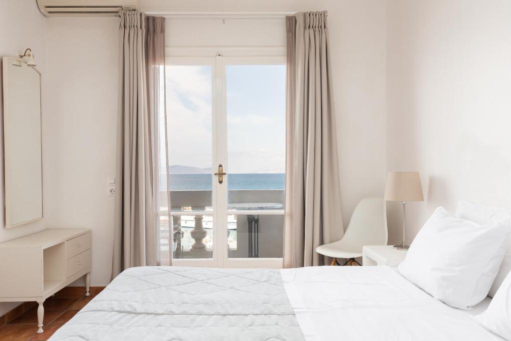 a white bedroom with a view of the ocean at Hotel Roumani in Spetses